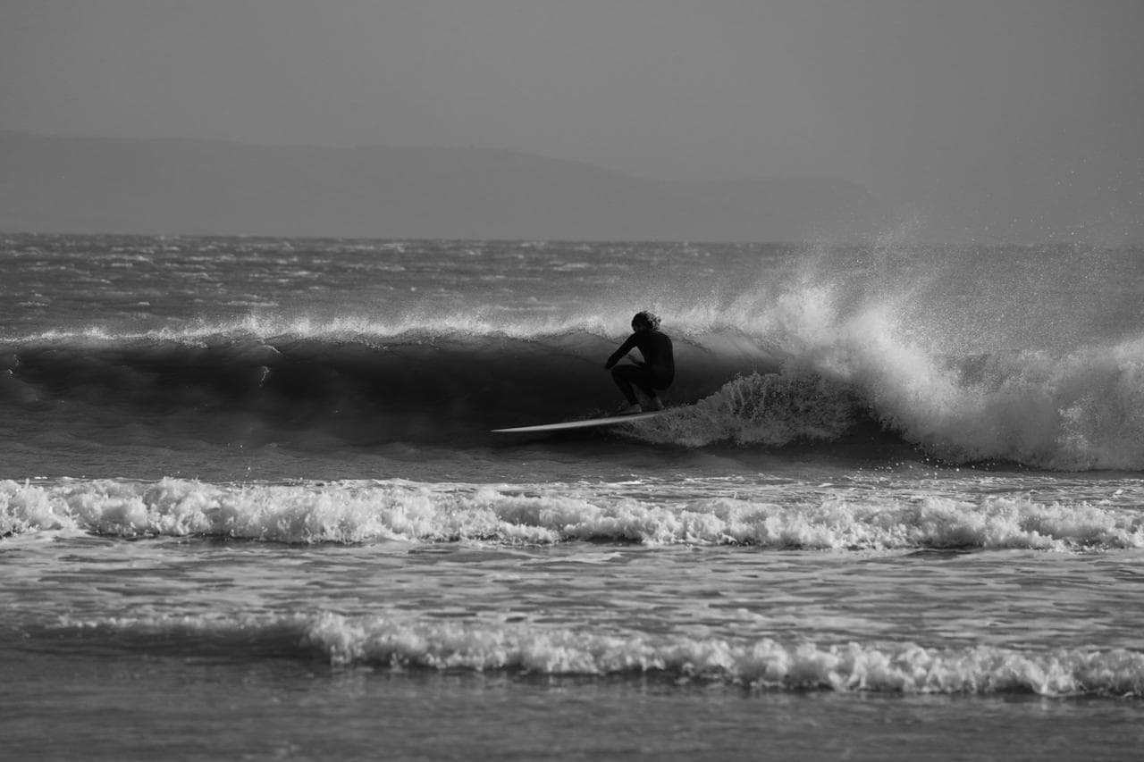 A longboarder riding a wave at Cap Sim